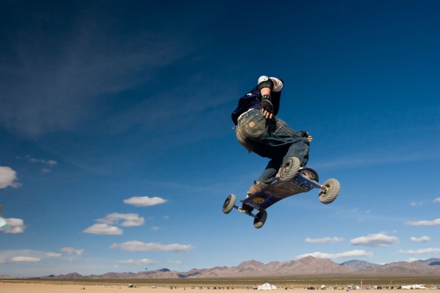 A mountainboarder in mid air with a deep blue sky