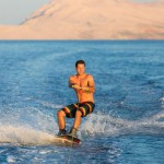 Wakeboarder in colorful shorts riding in sunset