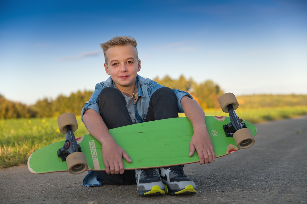 child holding his longboard and ready to use it on the road